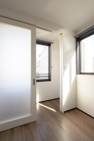 2DKの窓辺に物干し用のサンルームは2㎡。光を透過する３連吊り戸は、高さ2.2m